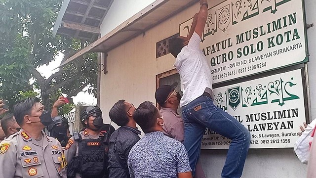 Polisi mencopot papan nama di kantor Khilafatul Muslimin Solo, Kamis (09/06/2022). FOTO: Agung Santoso