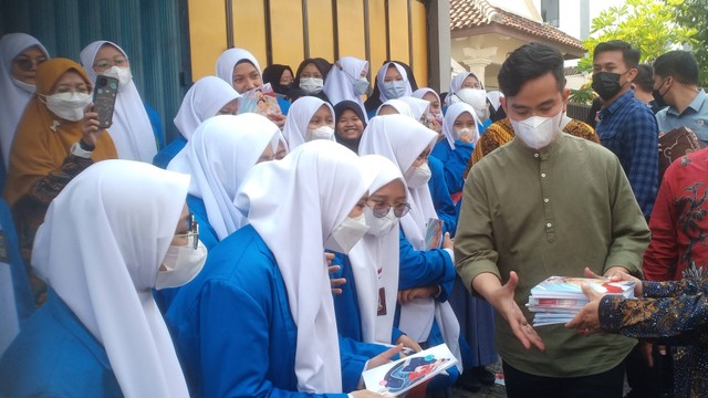 Wali Kota Solo, Gibran Rakabuming Raka, membagikan buku kepada siswa usai peletakan batu pertama di SMA Budi Utomo Solo, Kamis (16/06/2022). FOTO: Agung Santoso