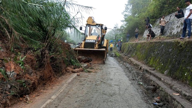 Alat berat tengah membersihkan material longsor terjadi di jalan daerah perbatasan Padang - Solok, Sumatera Barat, pada Kamis 23 Juni 2022. Foto: dok BPBD