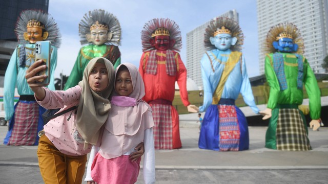 Warga berfoto di instalasi ondel-ondel yang dipamerkan di Taman Ismail Marzuki, Jakarta, Kamis (23/06/2022). Foto: Akbar Nugroho Gumay/Antara Foto