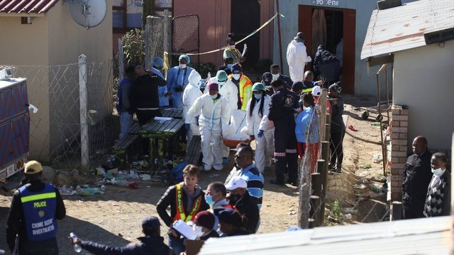 Petugas forensik mengevakuasi jenazah keluar dari pub kota di East London, Afrika Selatan pada Minggu (26/6/2022). Foto: STR/AFP