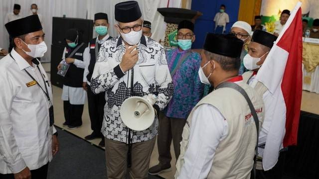 Gubernur Aceh Nova Iriansyah menguji dan menyerahkan alat pengeras suara ke petugas pada pelepasan jemaah haji kloter 1 Embarkasi Aceh, Selasa (14/6). Foto: Abdul Hadi/acehkini