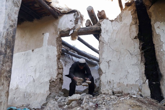 Seorang pria membersihkan sisa bebatuan akibat dilanda gempa di desa Spolgin di distrik Spera provinsi Khost, Afghanistan, Minggu (26/6/2022). Foto: Ali Khara/REUTERS