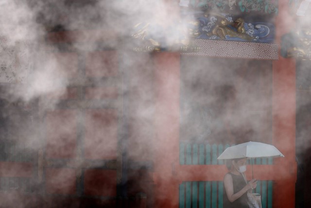 Seorang pengunjung Kuil Kanda Myojin terlihat melalui kabut dingin, saat gelombang panas melanda di Tokyo, Jepang, Selasa (28/6/2022). Foto: Kim Kyung-Hoon/REUTERS