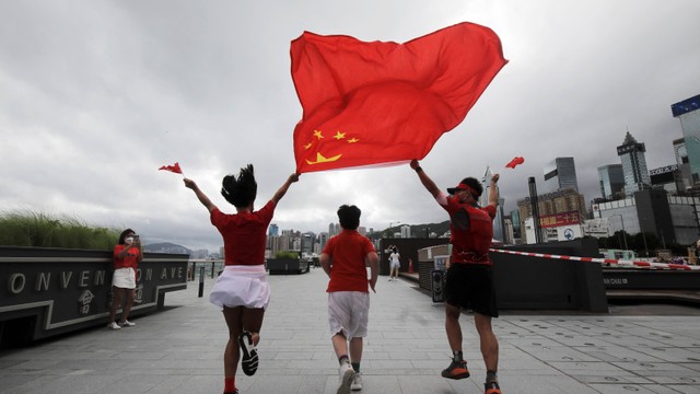 Warga berselebrasi dengan bendera China memperingati 25 tahun penyerahan Hong Kong ke Tiongkok di Convention Avenue, Hong Kong, Jumat (1/7/2022). Foto: Paul Yeung/REUTERS
