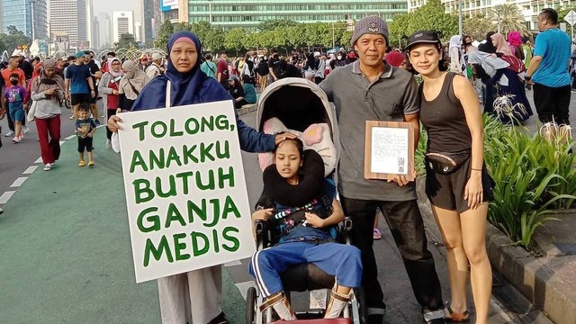 Santi Warastuti, bersama anaknya Pika, membawa poster tuntutan ganja medis dilegalkan di acara Car Free Day (CFD) Jakarta. Foto: Instagram/@santiwarastutisanti