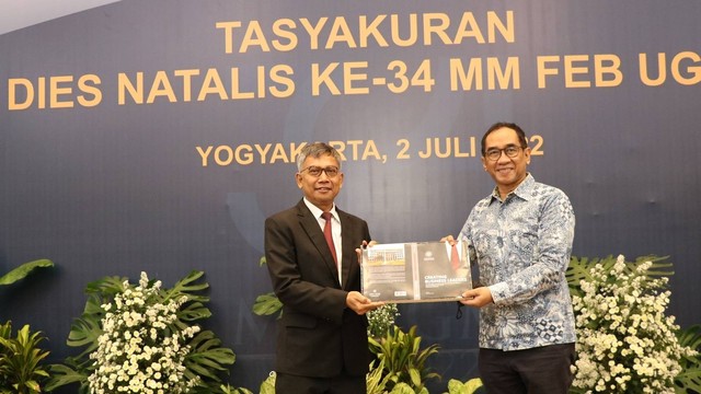 Penyerahan replika sampul buku dari ketua Prodi MM FEB UGM Amin Wibowo, kepada wakil Rektor Bidang Kerja Sama dan Alumni UGM Paripurna Sugarda. Foto: Humas UGM