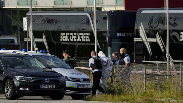 Petugas polisi berjalan dengan seseorang yang mengenakan pakaian pelindung putih di luar pusat perbelanjaan Fields, setelah insiden penembakan di lokasi tersebut, di Kopenhagen, Denmark, Minggu (3/7/2022). Foto: Ritzau Scanpix/Olafur Steinar Gestsson via REUTERS