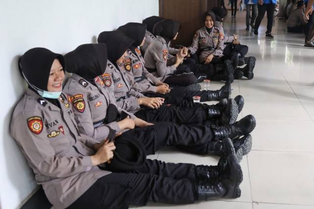 Personel Polisi Wanita (Polwan) Polda Aceh beristirahat saat melakukan pengamanan aksi demo di depan Gedung DPRA, Kota Banda Aceh, Kamis (26/9/2019). Foto: Suparta/acehkini