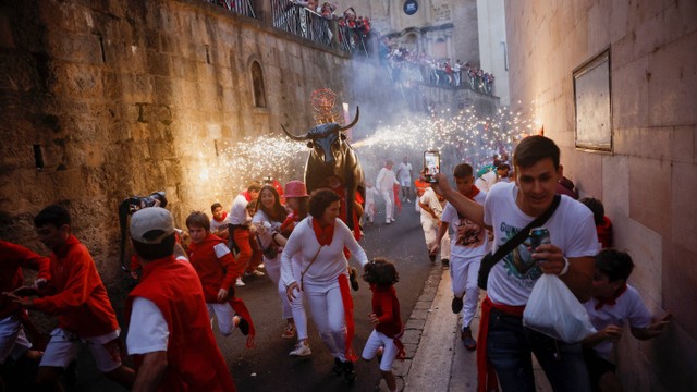 Orang-orang berlarian menghindari banteng fire bull yang membawa kembang api saat festival San Fermin di Pamplona, Spanyol, Rabu (6/7/2022). Foto: Juan Medina/REUTERS