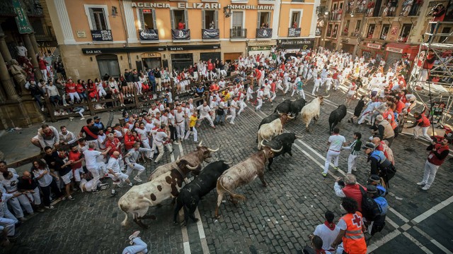 Peserta berlari di depan banteng selama "encierro" (lari banteng) festival San Fermin di Pamplona, Spanyol pada 8 Juli 2022. Foto: MIGUEL RIOPA/AFP