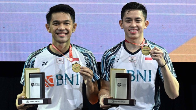 Fajar Alfian dan Muhammad Rian Ardianto berpose setelah mengalahkan Mohammad Ahsan dan Hendra Setiawan dari Indonesia dalam pertandingan final ganda putra di turnamen bulu tangkis Malaysia Masters di Kuala Lumpur, Minggu (10/7/2022). Foto: Mohd Rasfan/AFP