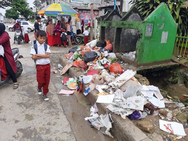 Seorang siswa SD berjalan di samping tumpukan sampah di Kota Kendari. Foto: Moch Ijah/kendarinesia.