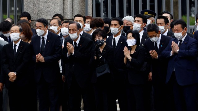 Anggota parlemen berdoa ke arah kendaraan yang membawa jenazah mantan Perdana Menteri Jepang Shinzo Abe, di depan Gedung Diet Nasional Jepang setelah pemakaman di Tokyo, Jepang, Selasa (12/7/2022). Foto: Kim Kyung-Hoon/REUTERS