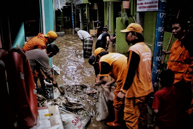 Petugas PPSU membersihkan lumpur usai air banjir di Kebon Pala, Kampung Melayu, Kecamatan Jatinegara, Jakarta Timur, Sabtu (16/7/2022). Foto: Jamal Ramadhan/kumparan