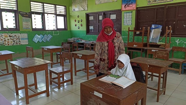 Seorang guru SDN Ngimbang, Kecamatan Palang, Kabupaten Tuban, saat mengajar satu-satunya siswa kelas 2 di SD tersebut. (foto: ayu/beritabojonegoro)