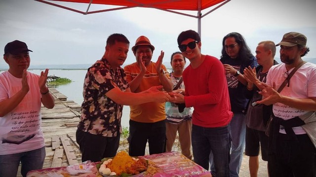 Eksekutif produser Hartono, menyerahkan potongan tumpeng kepada Addin Hidayat, pemeran utama pria film Uti deng Keke. Foto: Dok banthayo 