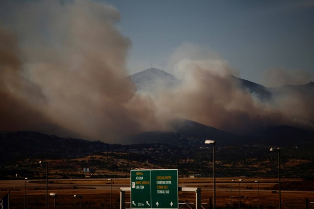 Helikopter pemadam kebakaran beroperasi saat api menyala di Gunung Penteli, di Athena, Yunani. Foto: Alkis Konstantinidis/REUTERS