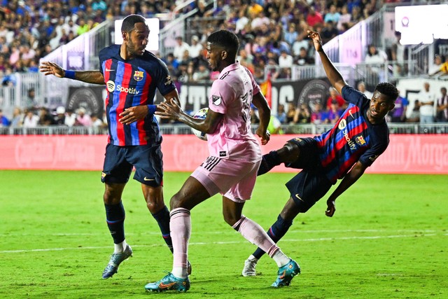 Penyerang FC Barcelona Pierre-Emerick Aubameyang duel dengan bek Inter Miami Damion Lowe dalam pertandingan persahabatan antara Inter Miami dan FC Barcelona di Stadion DRV PNK di Fort Lauderdale, pada Selasa (19/7/2022). Foto: Chandan Khanna/AFP