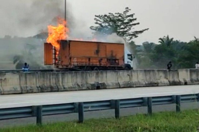 Truk kontainer terbakar di Tol Lampung, Kamis (21/7/2022) | Foto: Kadek Indra Daniawan/Pengendara yang melintas