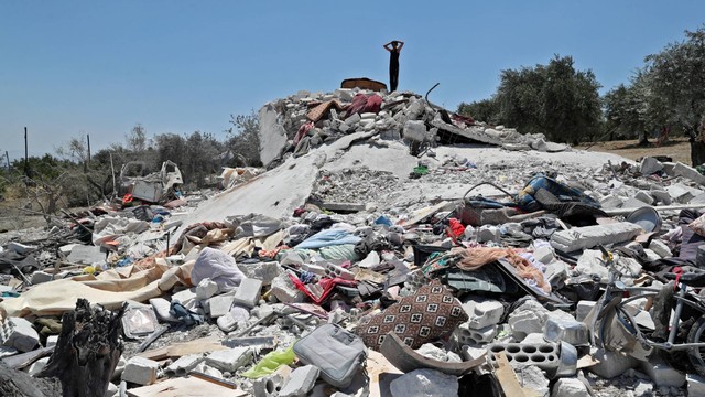 Seorang pemuda Suriah memberi isyarat di atas puing-puing akibat serangan udara Rusia, di Jisr al Shuqhur, provinsi Idlib, Suriah, Jumat (22/7/2022). Foto: Omar Haj Kadour/AFP
