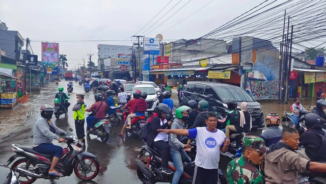 Petugas dibantu warga mengatur lalu lintas akibat banjir di kawasan Perempatan Mampang Jalan Raya Sawangan, Kecamatan Pancoran Mas, Kota Depok, Senin (25/7).  Foto: Dok. Istimewa