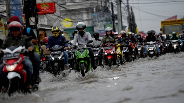 Pengendara motor melintasi banjir di kawasan perempatan Mampang, Pancoran Mas, Depok, Jawa Barat, Senin (25/7/2022). Foto: ANTARA FOTO/Sigid Kurniawan