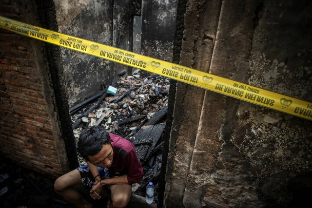 Warga duduk di depan rumahnya yang terbakar di Tambora, Jakarta, Selasa (26/7/2022). Foto: Rivan Awal Lingga/ANTARA FOTO