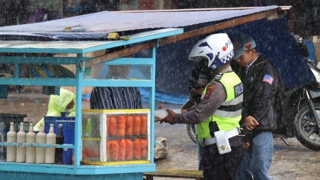 Personel Sat Lantas Polres Bukittinggi saat membagikan nasi kotak kepada salah seorang pedagang di Bukittinggi. Foto: Humas