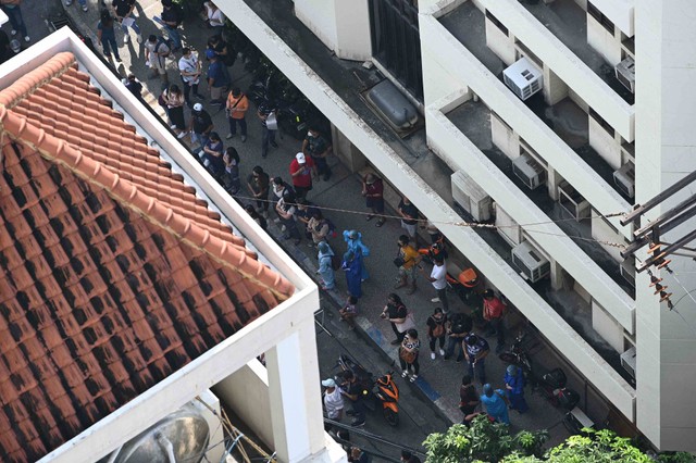 Karyawan sebuah kantor swasta berkumpul di luar gedung mereka akibat gempa di Manila, Filipina pada Rabu (27/7/2022). Foto: Ted Aljibe/AFP