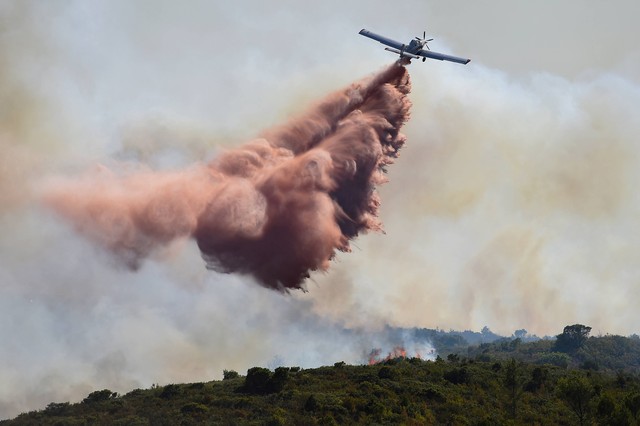 Pesawat pemadam kebakaran memadamkan kebakaran hutan di dekat Gignac, Prancis selatan, yang belum padam pada Selasa (26/7/2022). Foto: Sylvain Thomas/AFP