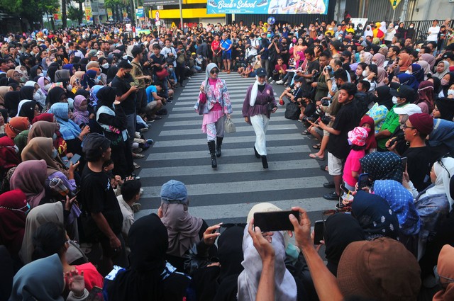 Peserta berjalan memperagakan busana dalam Muria Fashion Week 2022 yang digelar "Nadheera Luxury" di salah satu jalan di Kudus, Jawa Tengah, Minggu (31/7/2022). Foto: Yusuf Nugroho/Antara Foto