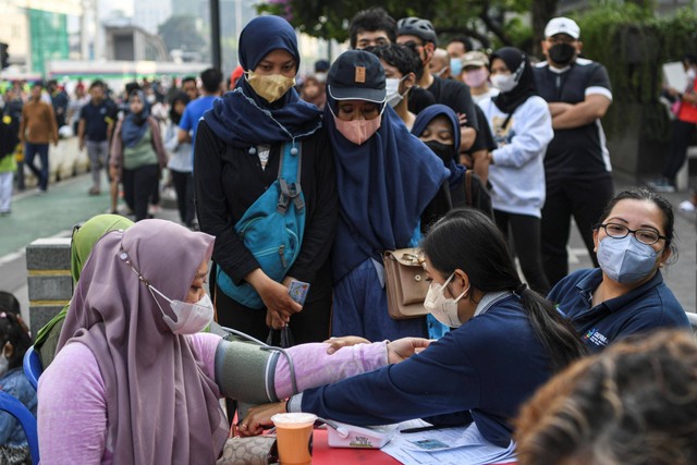 Petugas kesehatan memeriksa tekanan darah (tensi) dari warga sebelum mengikuti vaksinasi COVID-19 saat Car Free Day atau Hari Bebas Kendaraan Bermotor di kawasan MH Thamrin, Jakarta, Minggu (31/7/2022). Foto: M Risyal Hidayat/Antara Foto  