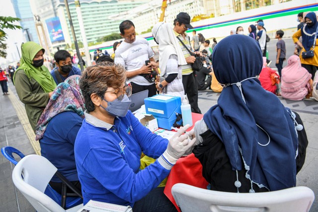 Petugas kesehatan menyuntikkan vaksin COVID-19 saat Car Free Day atau Hari Bebas Kendaraan Bermotor di kawasan MH Thamrin, Jakarta, Minggu (31/7/2022). Foto: M Risyal Hidayat/Antara Foto  
