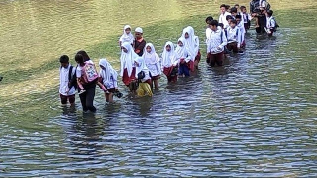 Siswa Sekolah Dasar Negeri (SDN) Padawaras  harus menantang maut menerobos air Sungai Ciujung yang kerap meluap di Desa Sukaluyu, Kecamatan Cikadu, Kabupaten Cianjur, Jawa Barat.  Foto: Dok. Istimewa