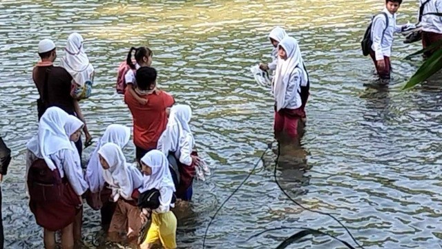 Siswa Sekolah Dasar Negeri (SDN) Padawaras harus menantang maut menerobos air Sungai Ciujung yang kerap meluap di Desa Sukaluyu, Kecamatan Cikadu, Kabupaten Cianjur, Jawa Barat. Foto: Dok. Istimewa