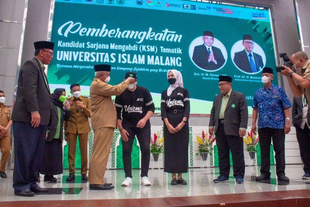 Bupati Malang Sanusi saat menyematkan topi kepada salah satu perwakilan mahasiswa Unisma Malang . Foto / dok