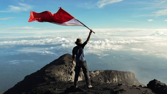 Pendaki yang mengibarkan bendera di Gunung Kerinci. Foto: Pegipegi