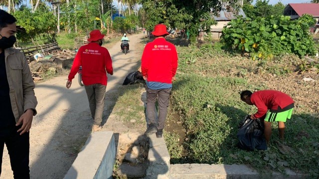 Personel BIN membantu warga di Desa Torue bersihkan sedimen lumpur yang terbawa banjir bandang di sekitar jalan dan rumah warga. Foto: Tim PaluPoso