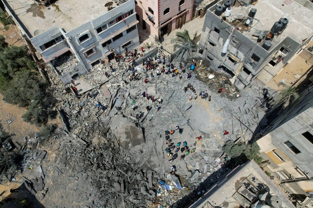 Warga Palestina memeriksa bangunan yang terkena serangan udara Israel, di Kota Gaza, Sabtu (6/8/2022). Foto: Mohammed Salem/REUTERS