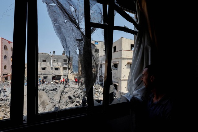 Warga Palestina melihat sebuah rumah yang terkena serangan udara Israel, di Kota Gaza, Sabtu (6/8/2022). Foto: Mohammed Salem/REUTERS