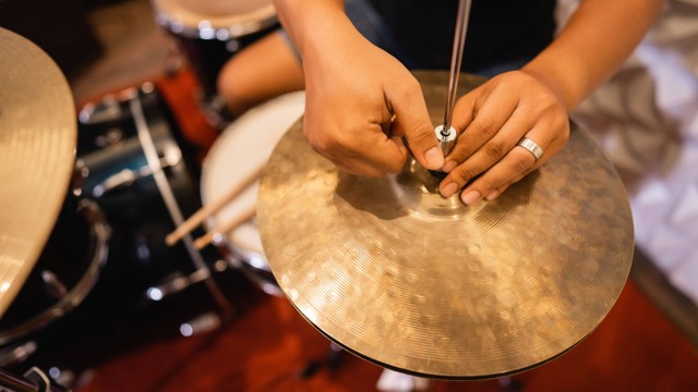 Seorang drummer menyiapkan hi-hat clutch cymbal sebelum digunakan. Foto: Odua Images/Shutterstock.