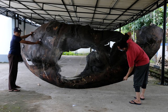 Koordinator Pelaksana Fungsi Layanan Balai Pengamatan Antariksa dan Atmosfer La Ode Muhammad Musafar (kanan) bersama petugas keamanan mengangkat pecahan roket Republik Rakyat Tiongkok (RRT) di LAPAN Pontianak, Kalimantan Barat, Sabtu (6/8/2022). Foto: Jessica Helena Wuysang/ANTARA FOTO