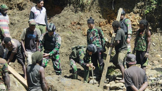 TNI dan warga menyingkirkan material longsor berupa bebatuan dan lumpur. (Foto Penrem 172/PWY