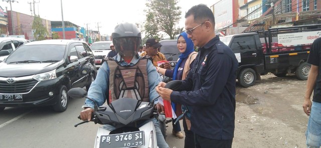 Ketua DPD Partai Nasdem Kota Sorong Ranley Mansawan memasangkan bendera merah putih kepada pengendara sepeda motor, foto: Yanti/BalleoNEWS