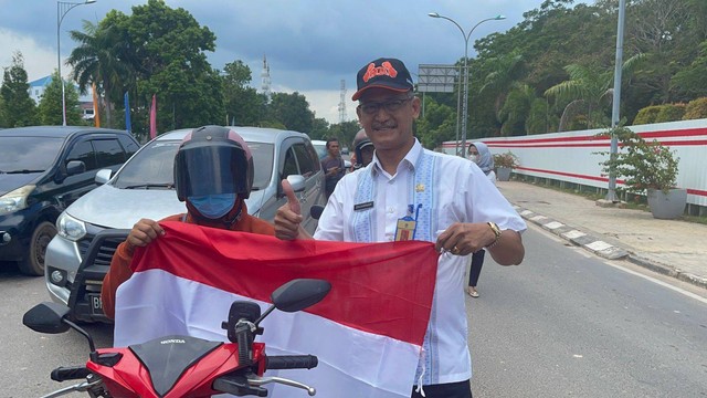 Kadispora Batam, Zulkarnain, menyerahkan bendera ke pengendara di Batam Center. Foto: Istimewa