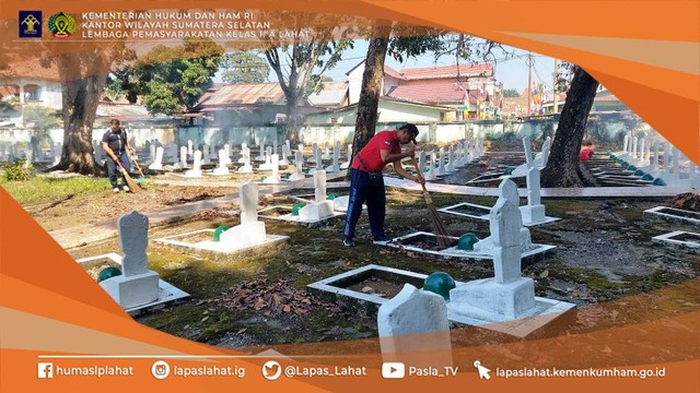 Kepala Lapas Lahat Kemenkumham Sumsel Soetopo Berutu terlihat sedang menyapu daun-daun kering di sekitar salah satu makam.