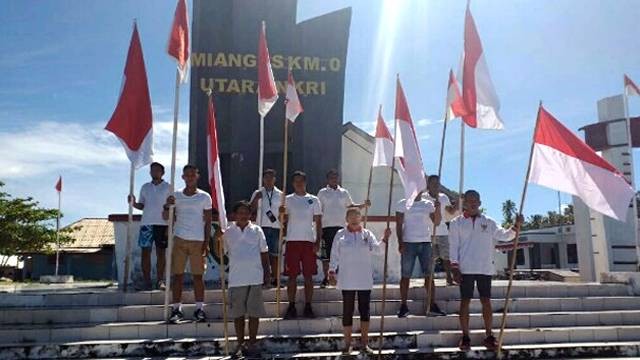 Warga di Pulau Miangas memasang bendera merah putih di tugu titk nol kilometer Indonesia.