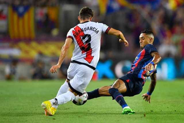 Bek Spanyol Rayo Vallecano Fran Garcia (kiri) ditekel oleh pemain depan Barcelona asal Brasil Raphinha selama pertandingan sepak bola liga Spanyol antara FC Barcelona dan Rayo Vallecano de Madrid di stadion Camp Nou di Barcelona pada 13 Agustus 2022. Foto: PAU BARRENA/AFP