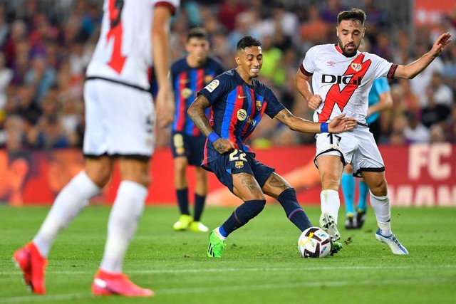 Pemain depan Barcelona, Raphinha, bersaing dengan gelandang Spanyol Rayo Vallecano, Unai Lopez (kanan) pada pertandingan Liga Spanyol antara FC Barcelona dan Rayo Vallecano de Madrid di stadion Camp Nou di Barcelona pada 13 Agustus 2022. Foto: PAU BARRENA/AFP